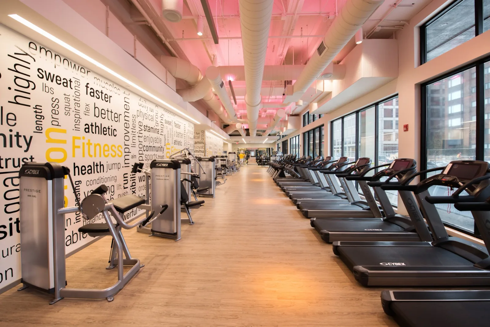 Long fitness room with cardio machines and strength equipment