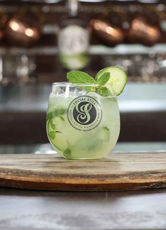 Green cocktail in a Social Still branded glass