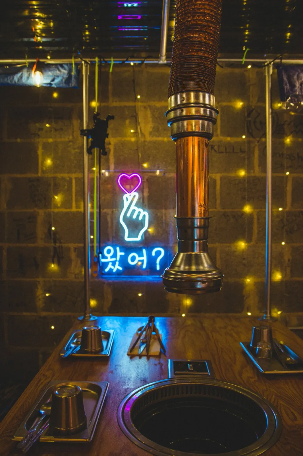Table grill and neon sign inside Pocha Street