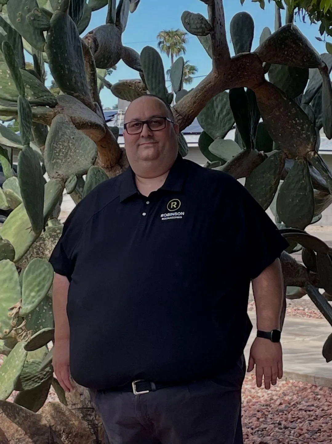 Rob Robinson in an R Robinson Bookkeeping polo, standing in front of prickly pear cactus
