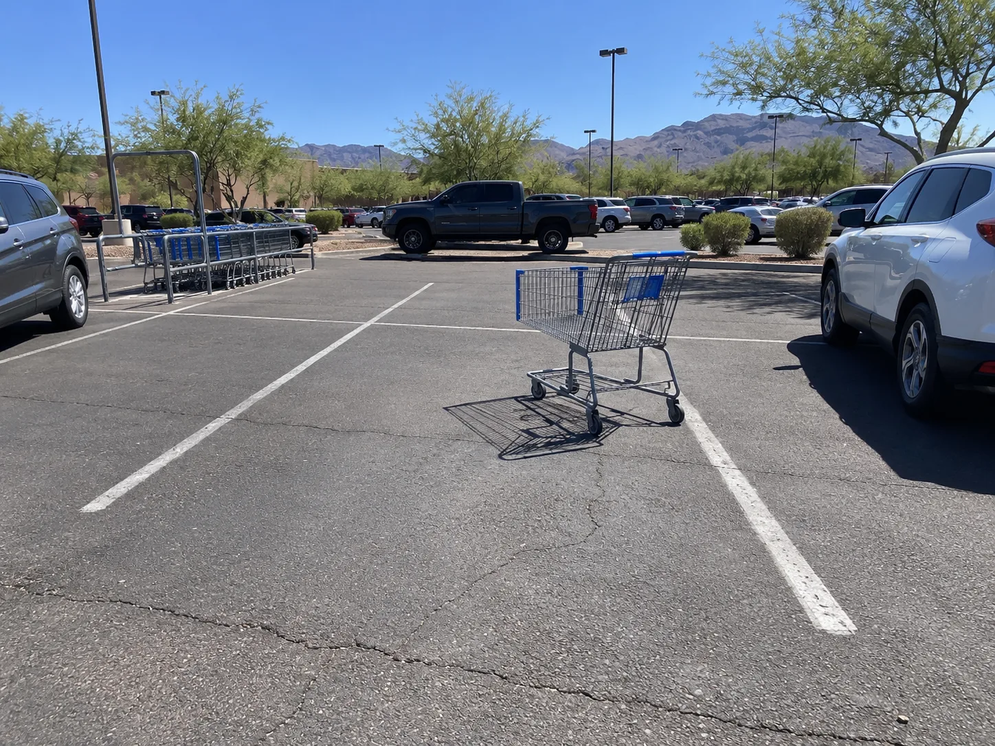 A shopping cart left in an open parking space near the cart return