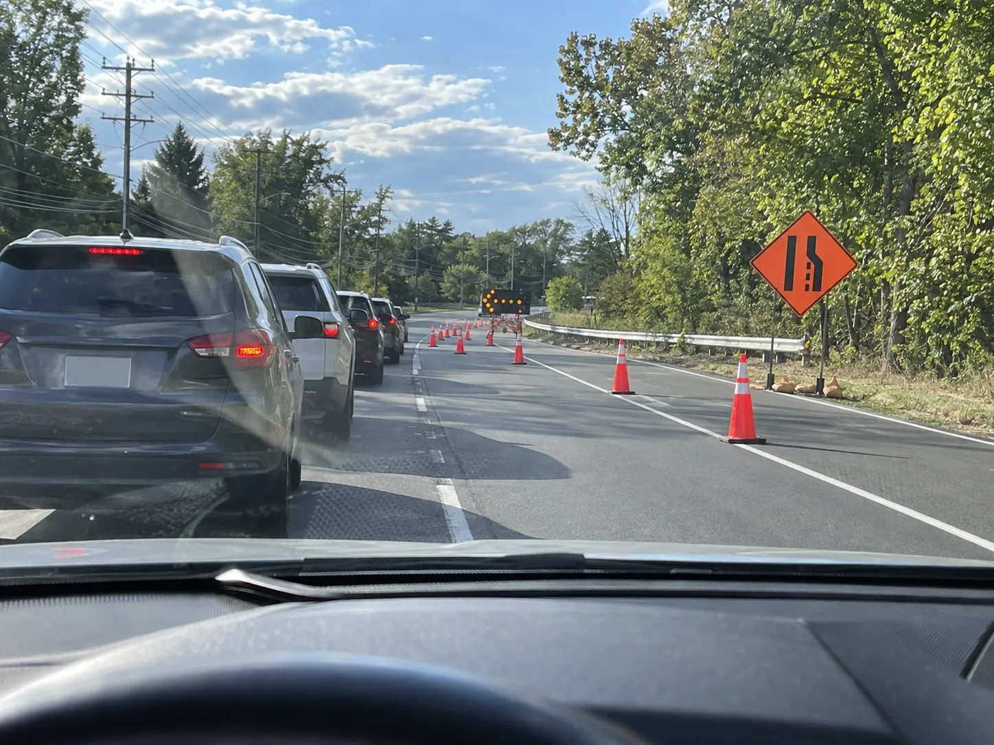 Cars lined up in one lane while the closing lane ahead sits empty